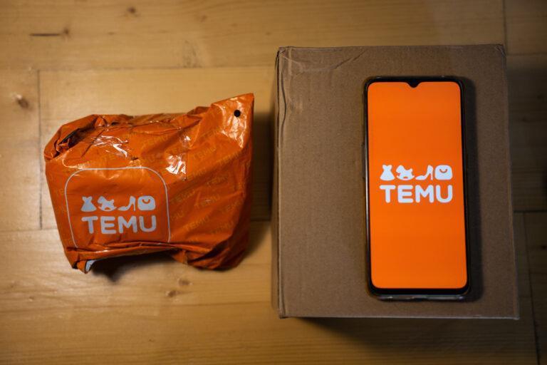 Pomarańczowa paczka z logo Temu, a obok niej smartfon również z logiem Temu