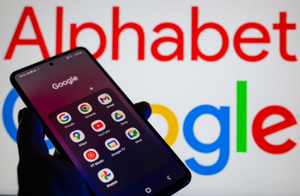 Zdjęcie przedstawi telefon na tle logo Google i Alphabet