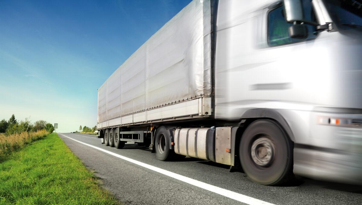 Na zdjęciu mknący po drodze samochód ciężarowy.