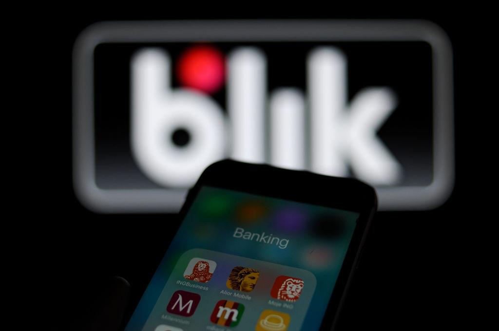 Na zdjęciu: telefon z aplikacjami bankowymi, w tle logo BLIKA