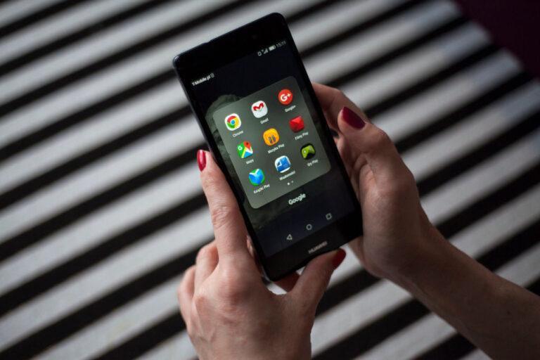 Zdjęcie przedstawia kobietę trzymającą telefon