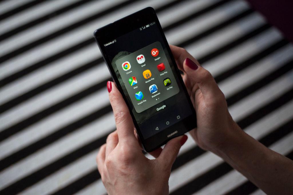 Zdjęcie przedstawia kobietę trzymającą telefon