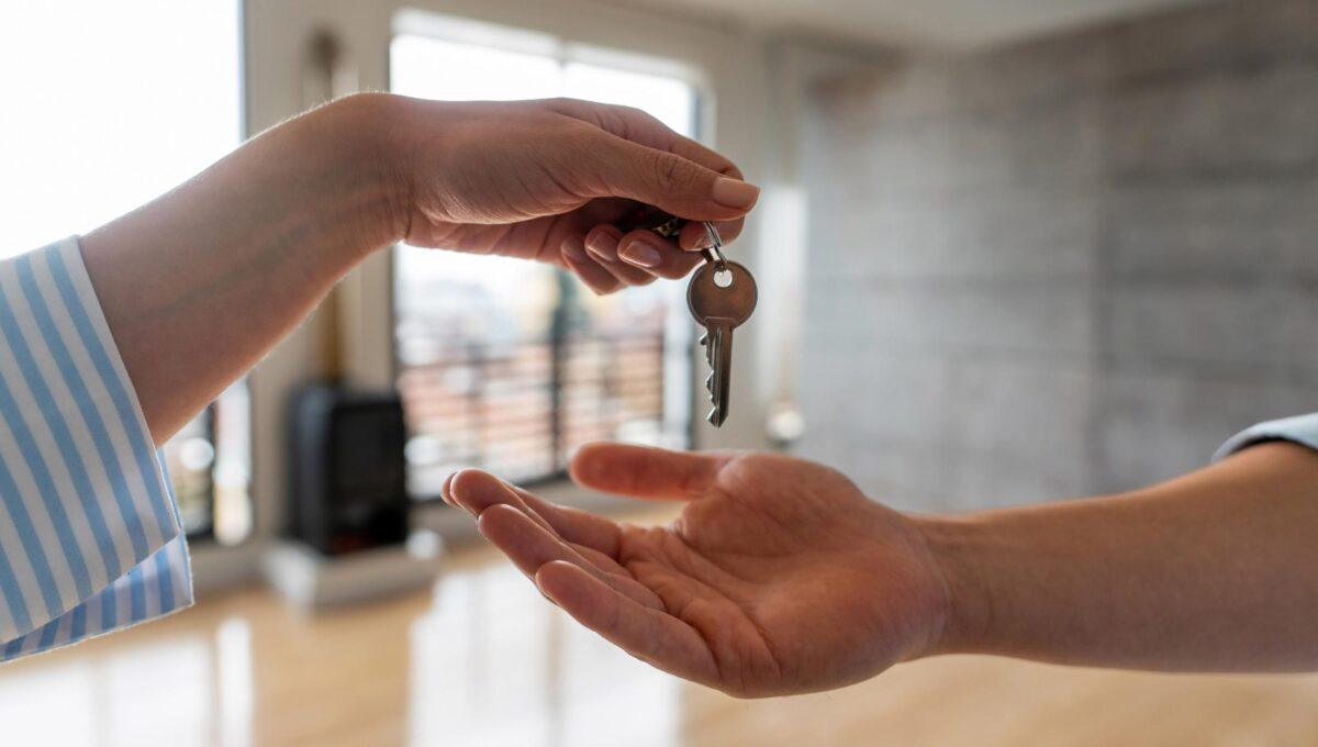 Zdjęcie przedstawia jedną osobę wręczającą drugiej klucze do mieszkania