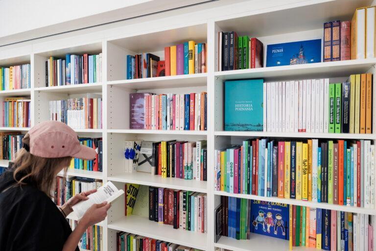 Na zdjęciu kobieta, która ogląda książki na półce