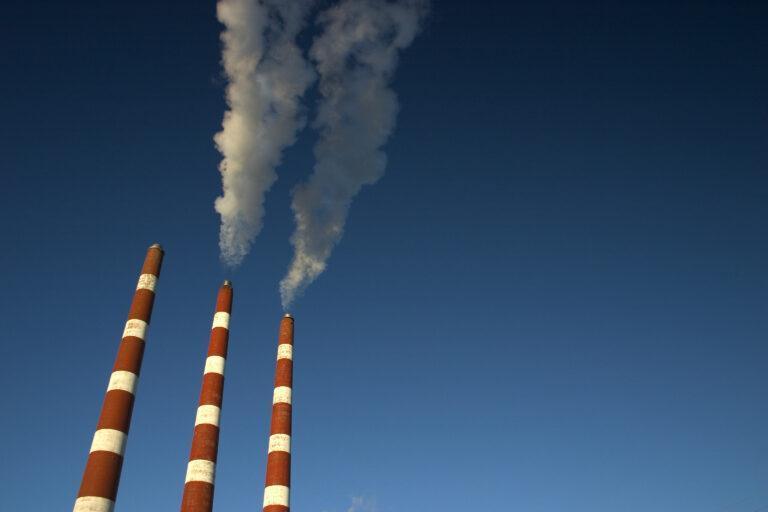 Na zdjęciu dymiące kominy na tle bezchmurnego nieba