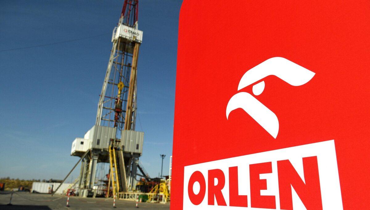 Zdjęcie przedstawia logo Orlenu na tle infrastruktury wydobywczej