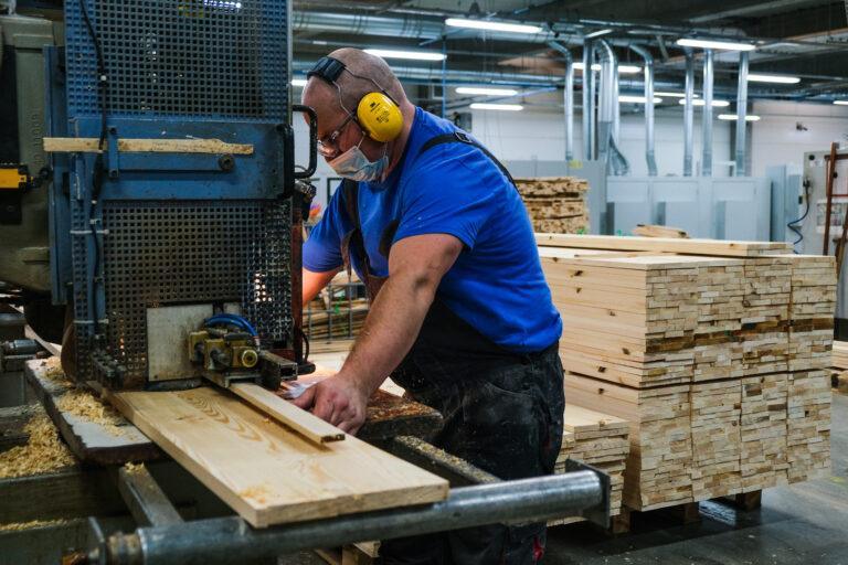 Pracownik fabryki trumien tnie deskę