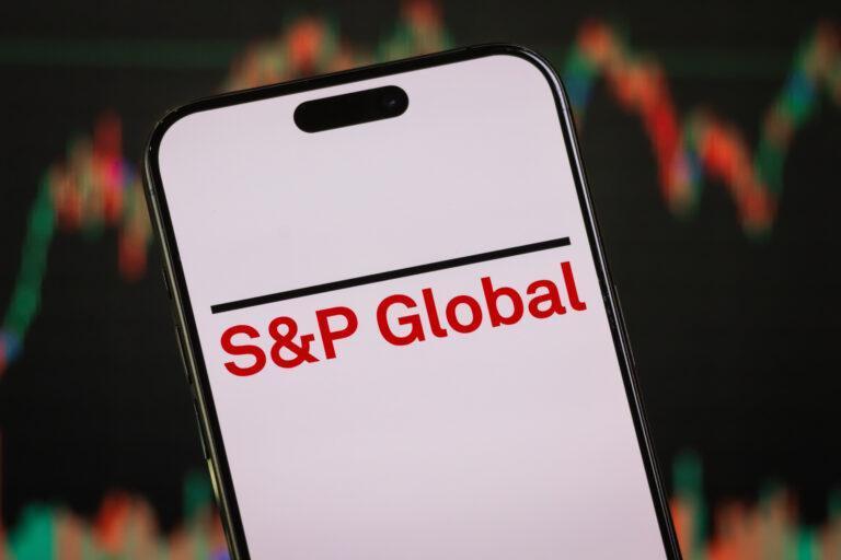 Na zdjęciu logo S&P Global wyświetlone na smartfonie na tle wykresu giełdowego