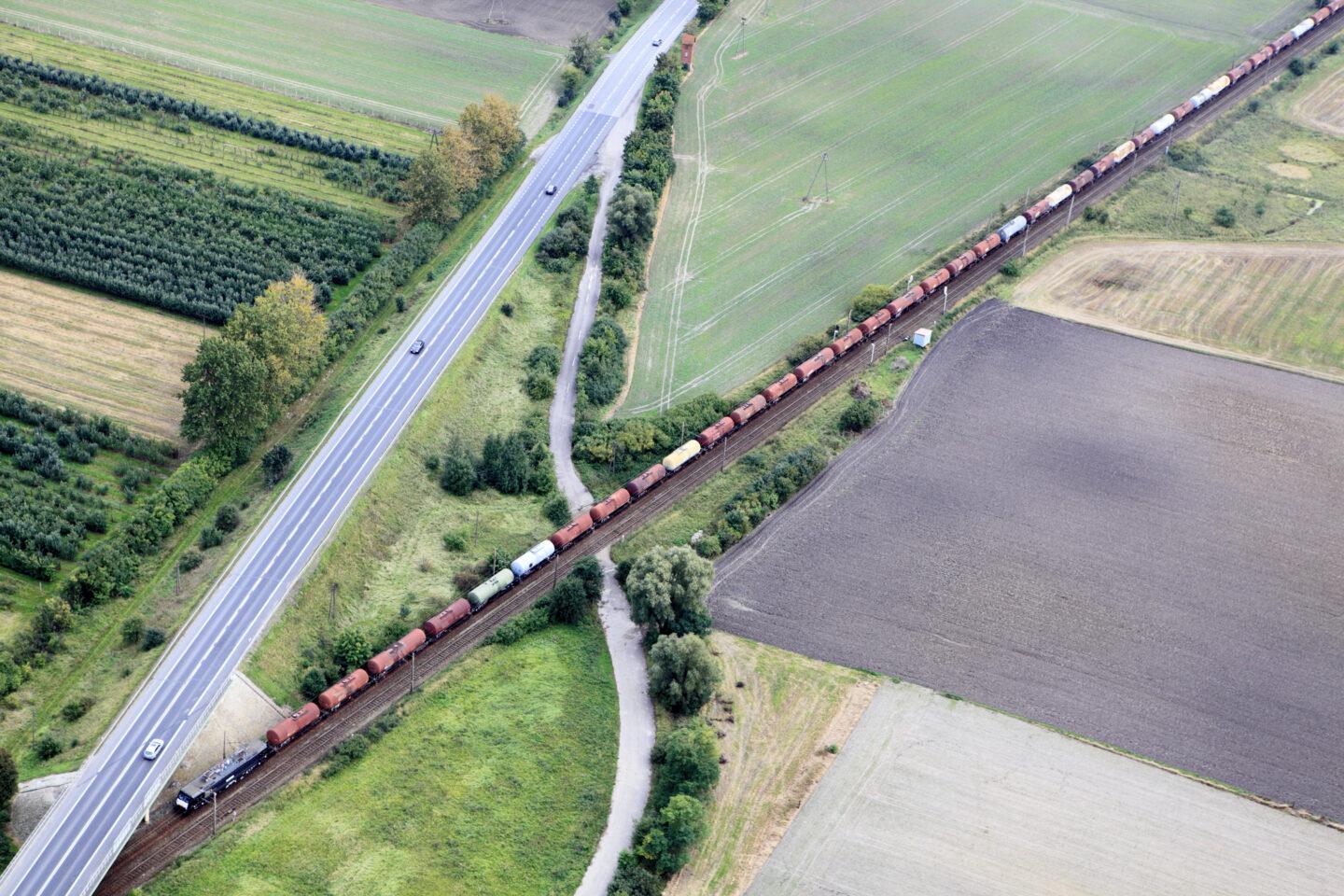 Na zdjęciu pociąg towarowy i droga widziane z lotu ptaka.