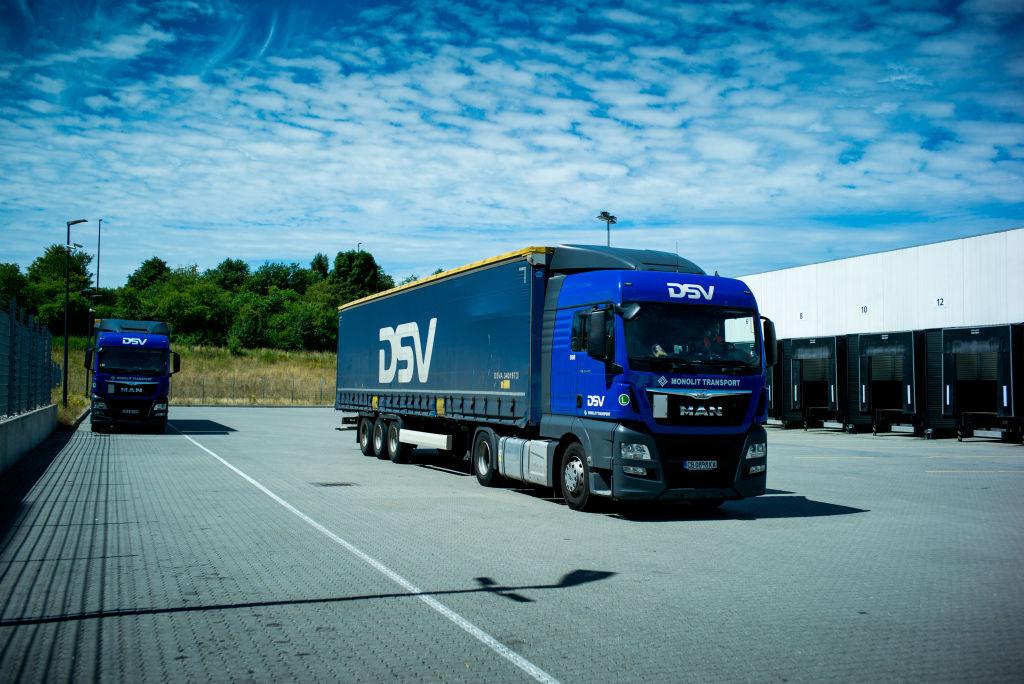 Na zdjęciu granatowe samochody ciężarowe z białym logo firmy DSV.