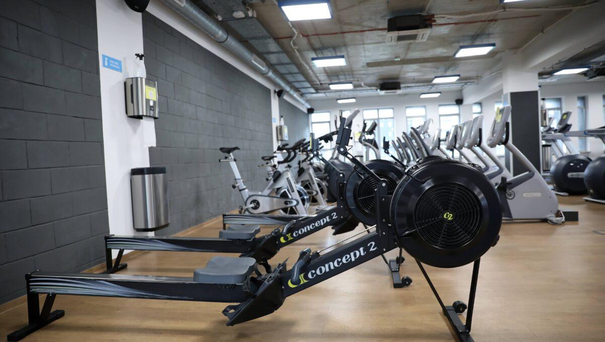 Wnętrze siłowni, na zdjęciu znajdują sprzęt do ćwiczeń, w tym między innymi rowerki stacjonarne