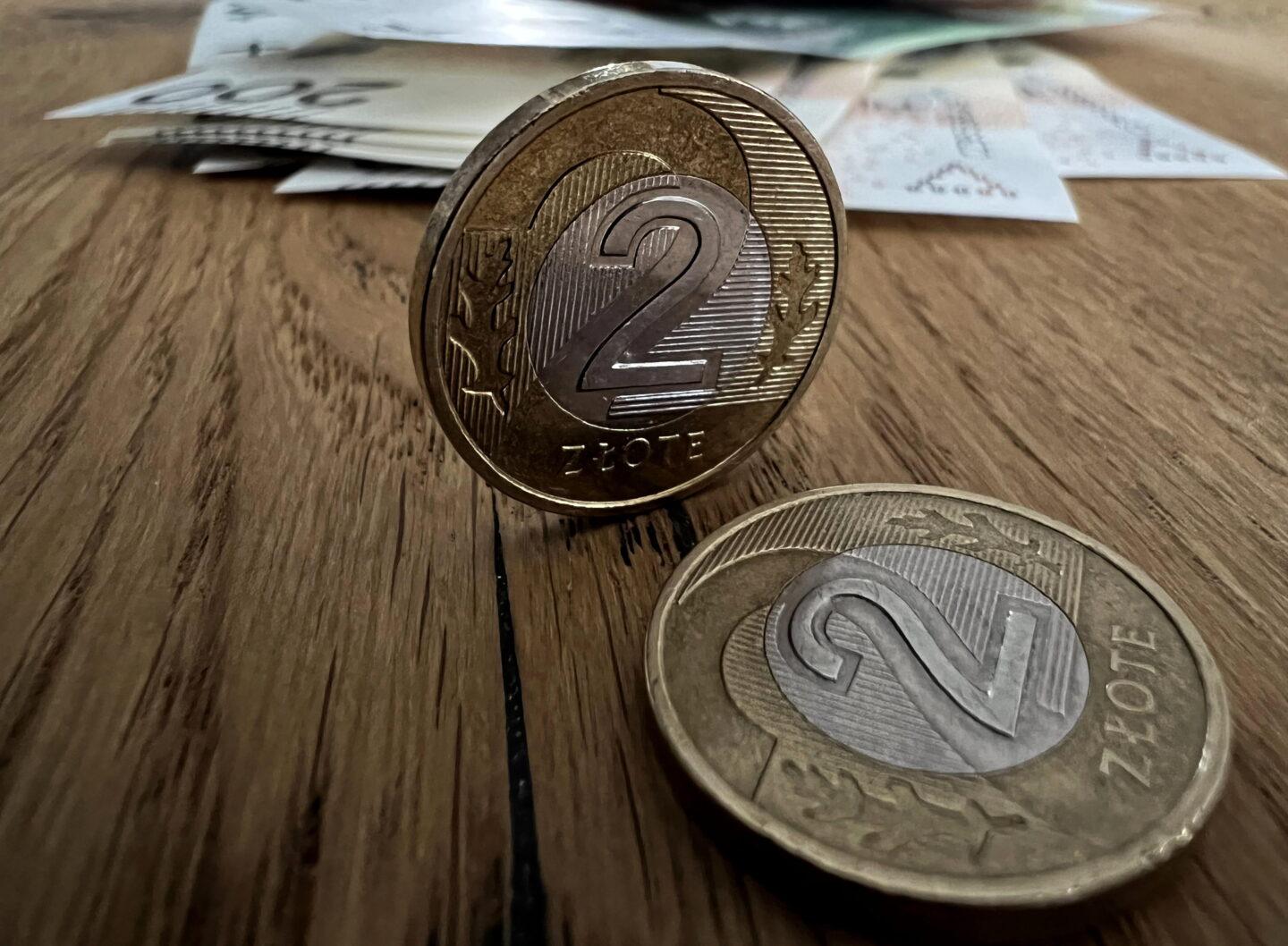 Dwie monety dwuzłotowe, a w tle banknoty NBP