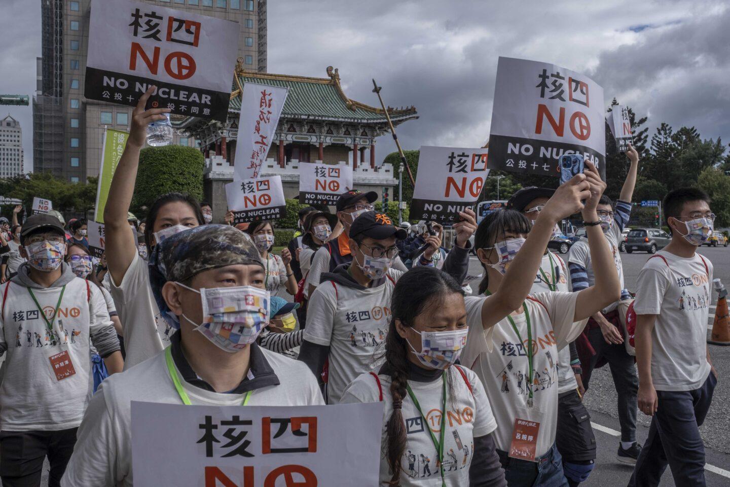 Protestujący z banerami antynuklearnymi na tle świątyni w Tajpej