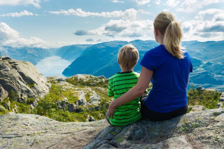 Matka z dzieckiem spoglądają w dół na Lysefjorden w Norwegii. W pobliżu słynnej Preikestolen, znanej także jako Ambona.