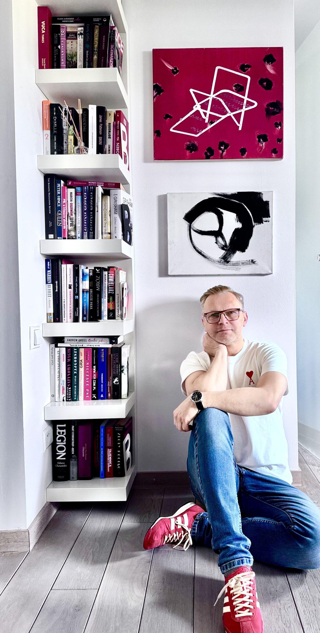 Bartosz Berestecki, prezes spółki PayTel. W tle obrazy: czerwony Joanna Mlącka „Ogniska choroby”, biały Norman Leto „Sequence 2012”