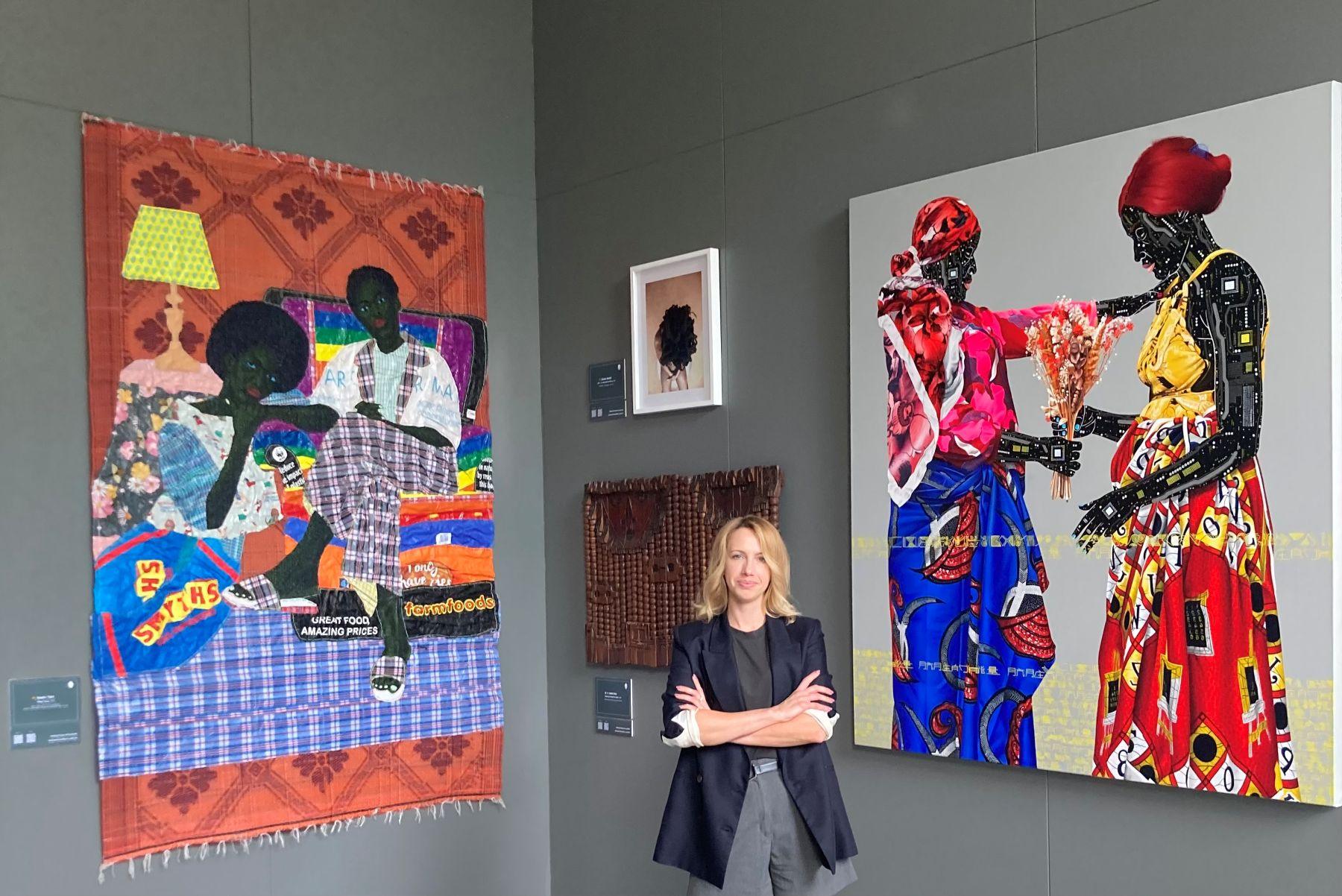 Natalia Bradbury, kuratorka wystawy. Po lewej praca autorstwa Kwaku Yaro z wykorzystaniem toreb na zakupy, po prawej praca Eddy’ego Kamuangi poruszająca temat wydobycia koltanu i powiązanych z tym zagrożeń dla zdrowia kobiet.