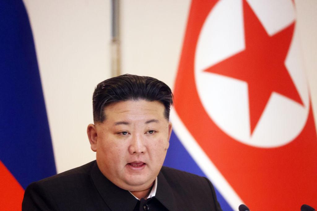 Kim Dzong Un na tle północnokoreańskiej flagi