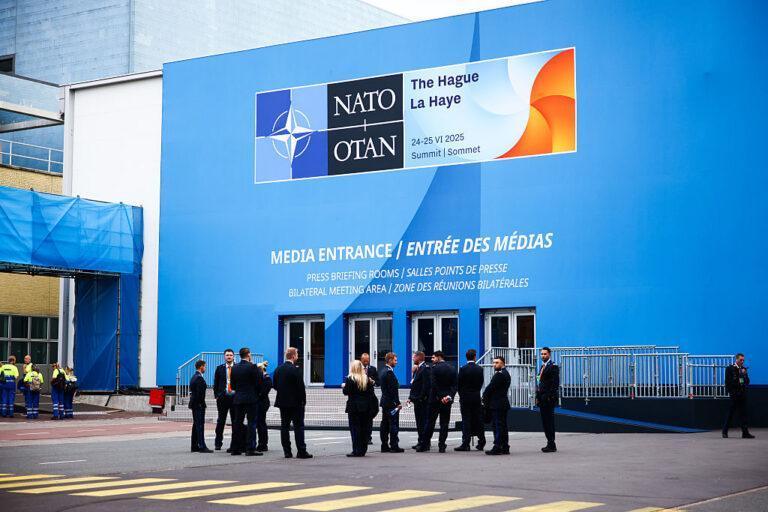 Na zdjęciu ludzie przed wejściem do obiektu z logo Szczytu Nato