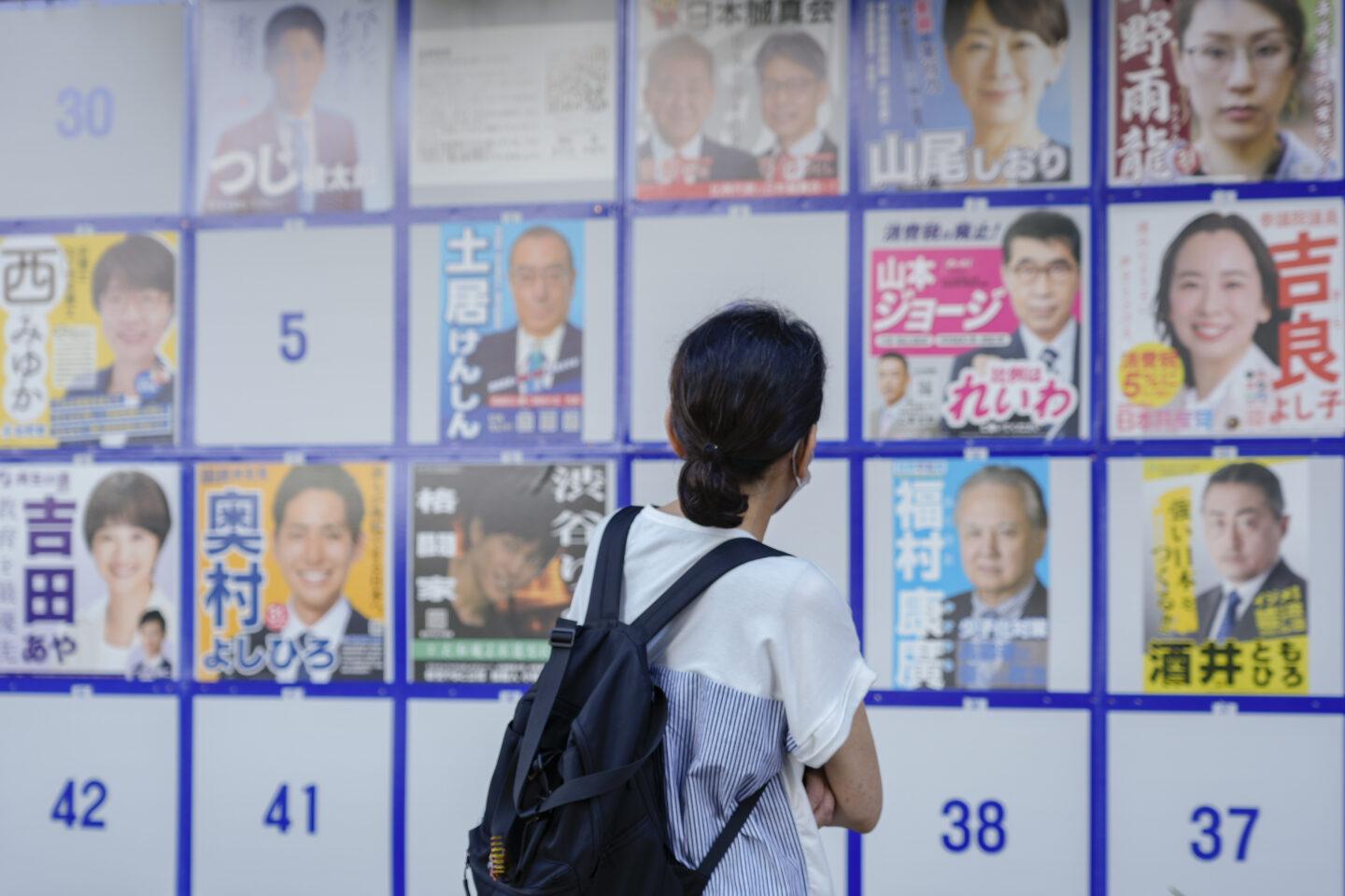 Kobieta patrzy na plakaty wyborcze w Tokio