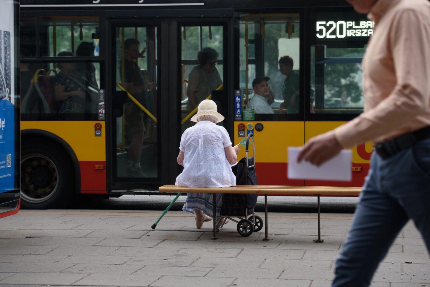 Na zdjęciu starsza osoba na przystanku autobusowym