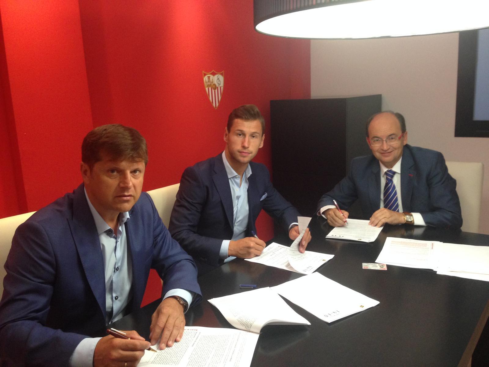 Na zdjęciu piłkarz Grzegorz Krychowiak podpisuje kontrakt z klubem Sevilla FC. Obok piłkarza siedzi Cezary Kucharski (jego menedżer)