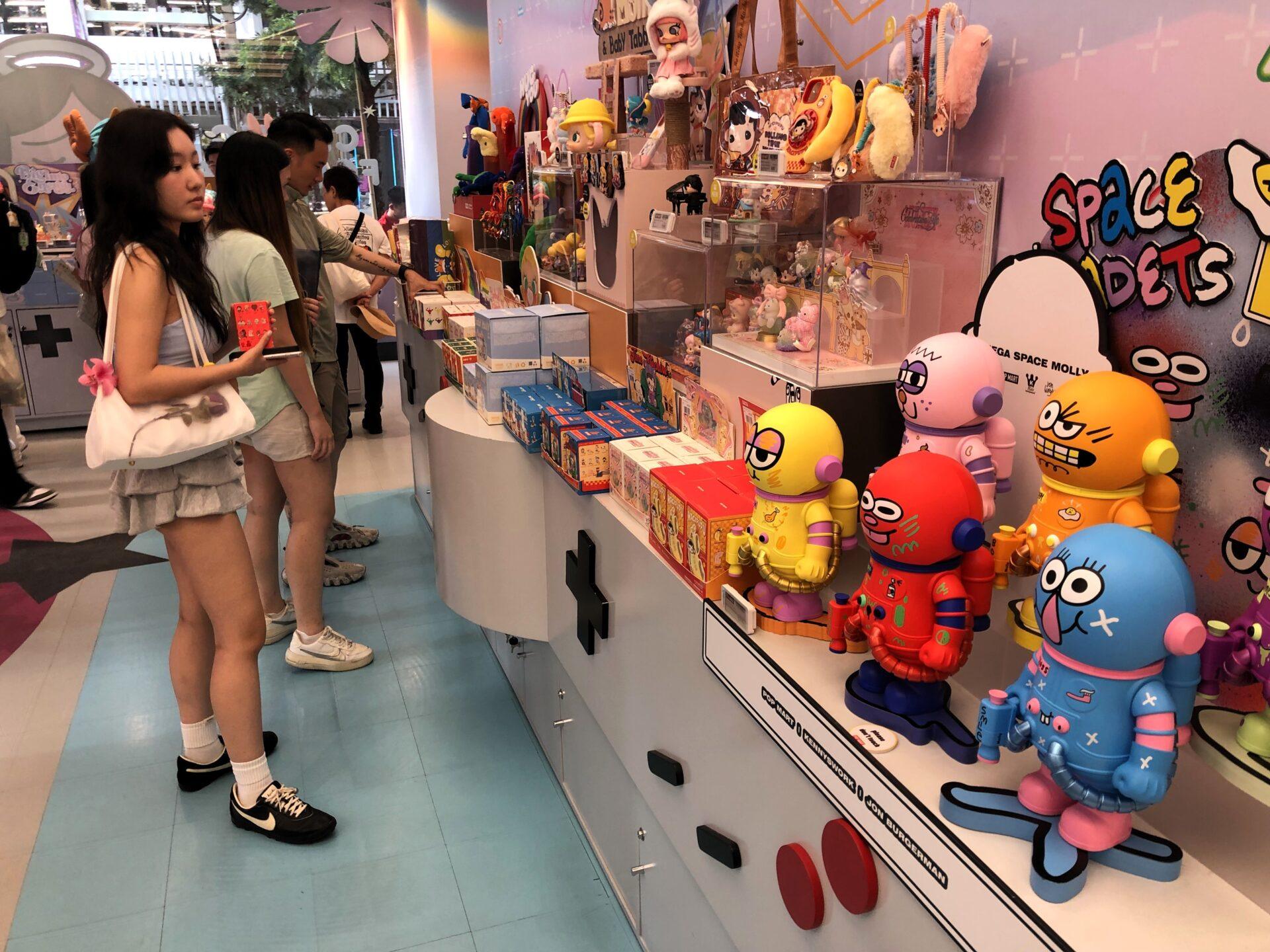 Klienci patrzą na kolorowe figurki Pop Mart