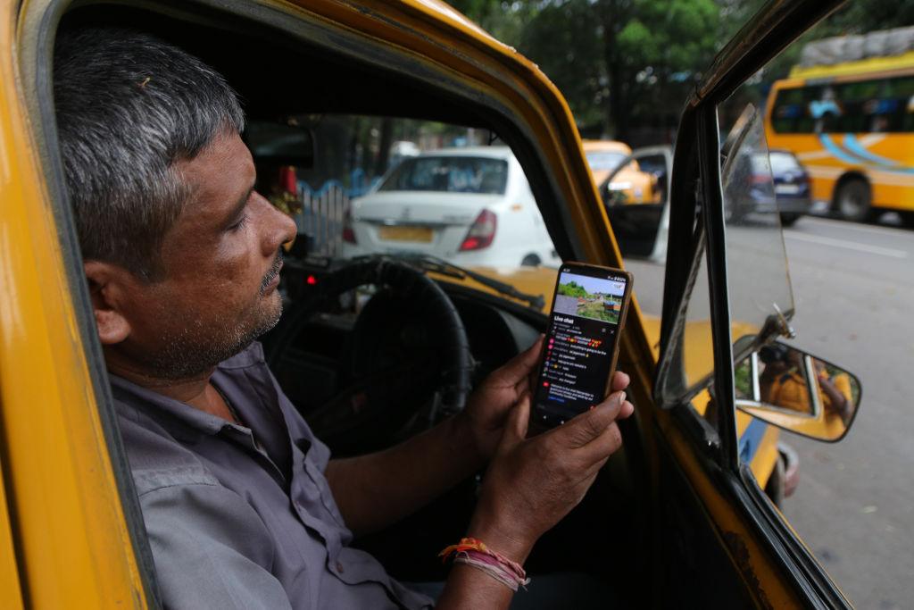 Mężczyzna w żółtym samochodzie trzyma smartfon