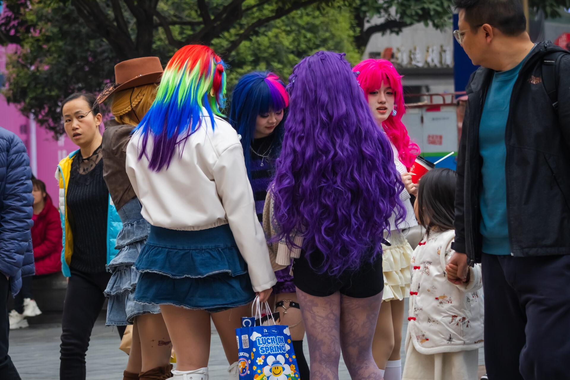 Grupa młodych kobiet w kolorowych perukach