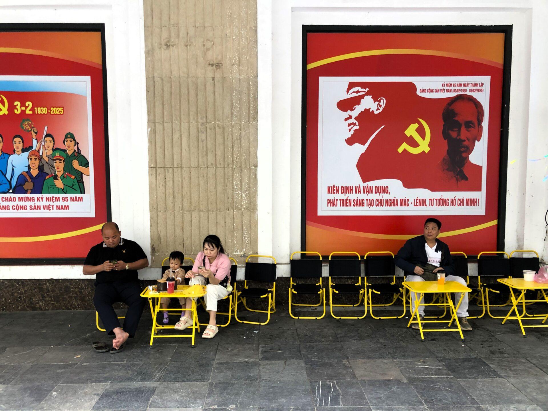 Ludzie przy stolikach pod bilbordami