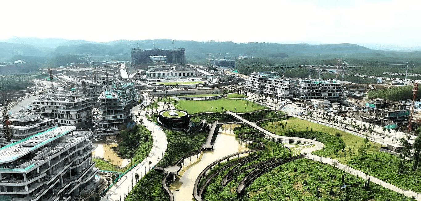 Panorama z nieukończonymi budynkami i dźwigami w zielonej scenerii