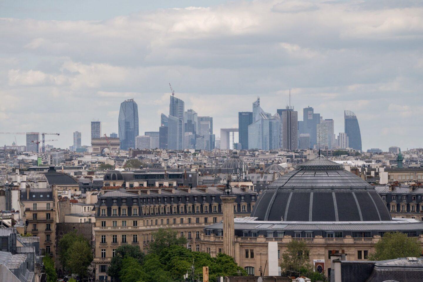 Zdjęcie przedstawia panoramę Paryża z biurowcami w tle