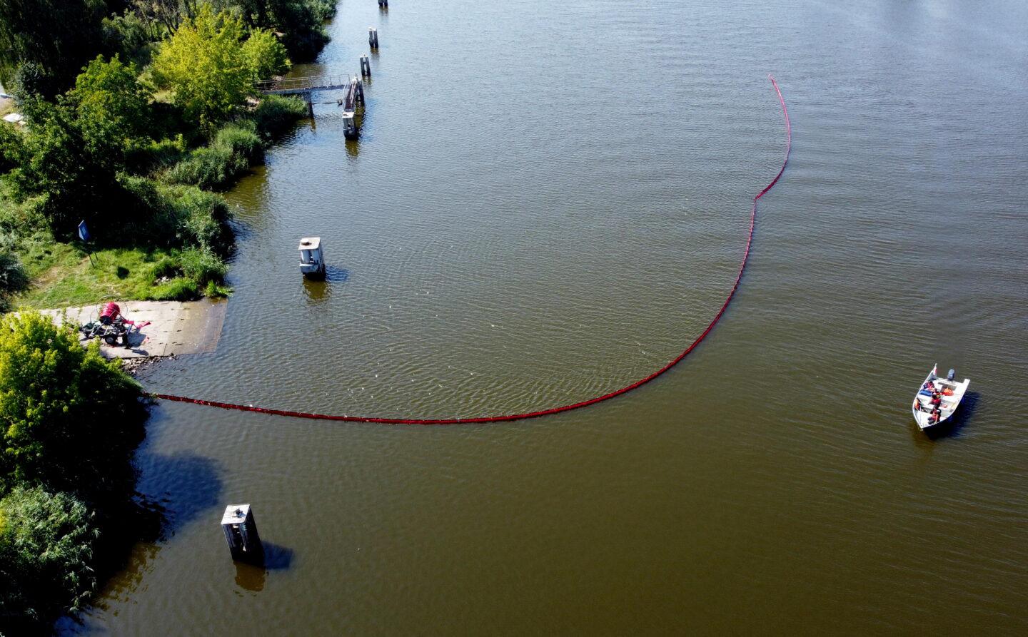 Gryfino, 16.08.2022. Strażacy z Państwowej Straży Pożarnej stawiają na Odrze kolejną zaporę elastyczną mającą za zadanie wyłapywanie śniętych ryb, 16 bm. w Gryfinie. Fot. PAP/Marcin Bielecki