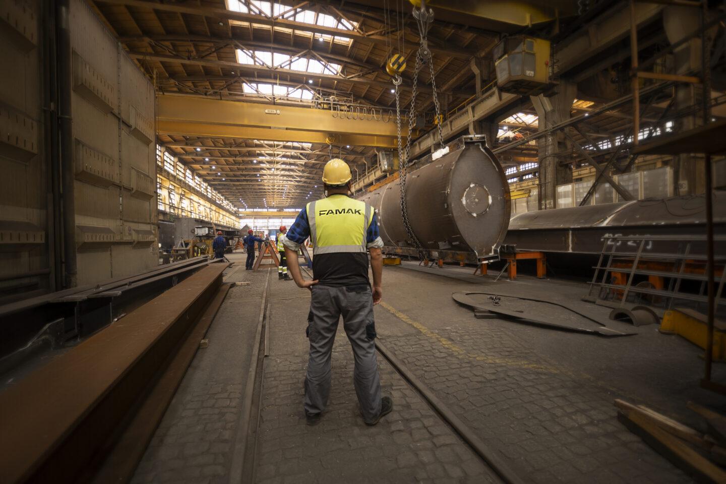 Zdjęcie pokazuje pracowników fabryki Famak wewnątrz hali produkcyjnej.