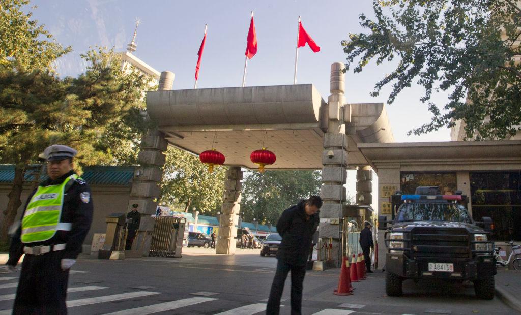 Dwie osoby stoją przed bramą ozdobioną czerwonymi flagami i lampionami