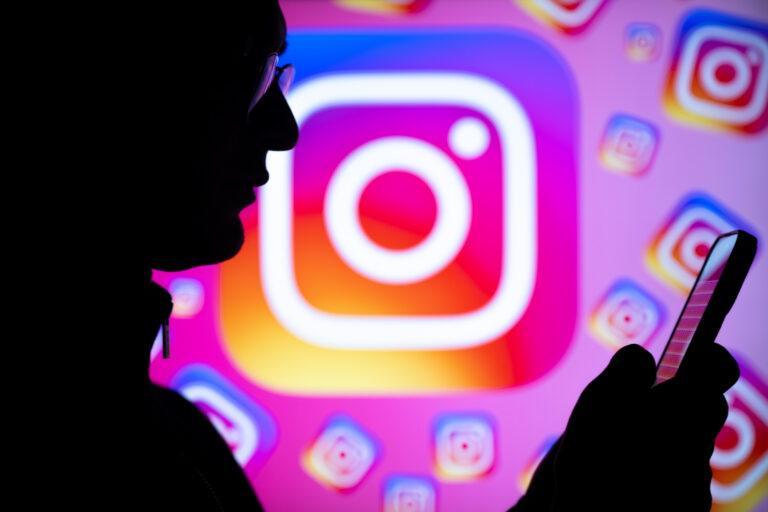 Na pierwszym planie osoba trzymająca telefon, na drugim logo Instagrama