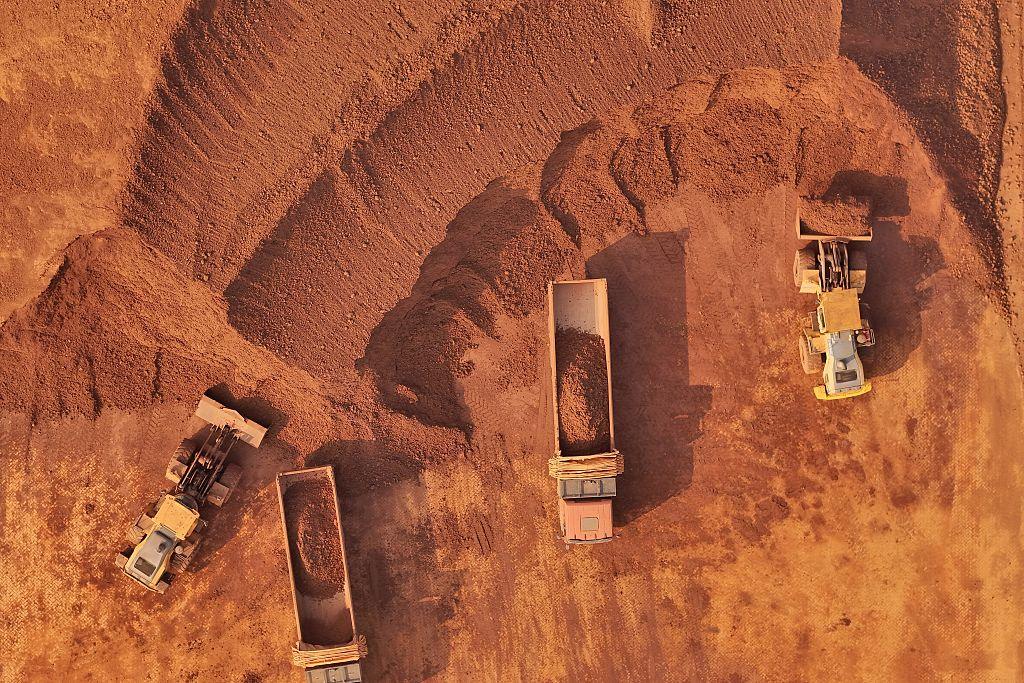 Widziane z góry ciężarówki wypełnione czerwoną rudą metali