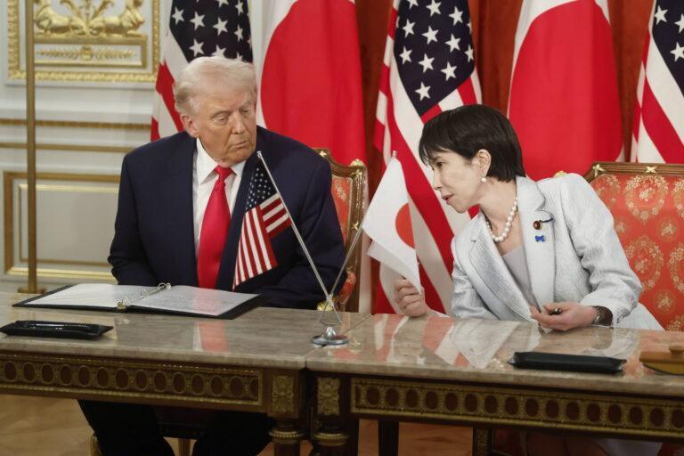 Donald Trump i Sanae Takaichi siedzą przy stole na tle amerykańskich i japońskich flag