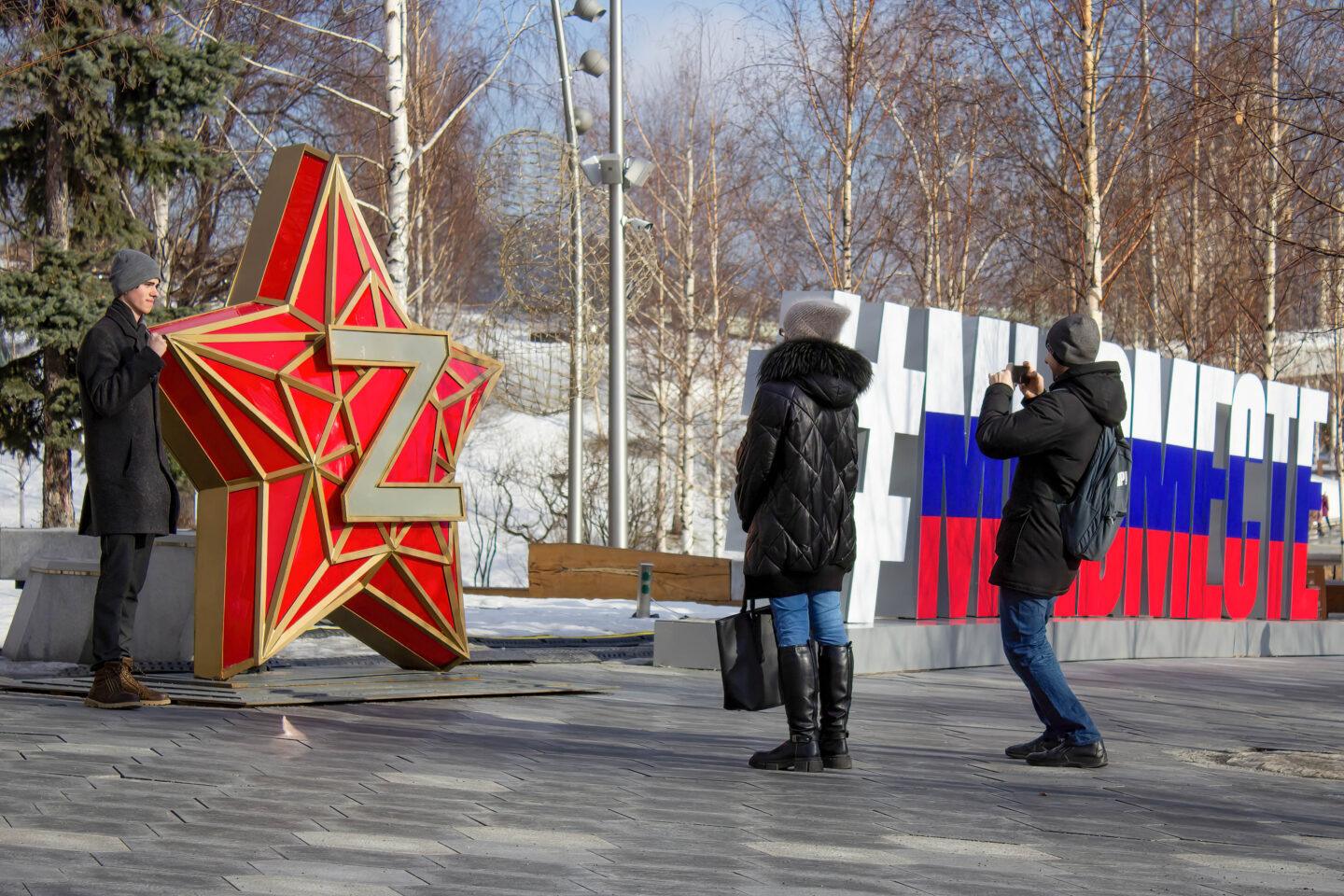 Na zdjęciu z marca 2023 r. mieszkańcy Moskwy robiący sobie zdjęcia na tle sowieckiej czerwonej gwiazdy z literą "Z", która stała się symbolem rosyjskiej napaści na Ukrainę