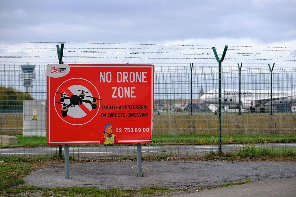 Na zdjęciu ogrodzenie otaczające lotnisko w Brukseli i baner informujący o zakazie lotów dronami