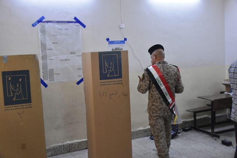 mężczyzna w mundurze wrzuca kartkę do urny wyborczej