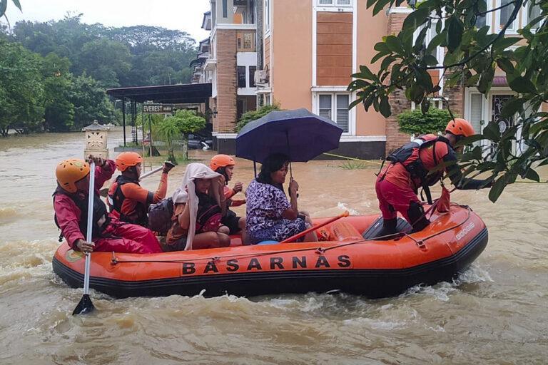 Ratownicy ewakuują pontonem mieszkańców z zalanej miejscowości.