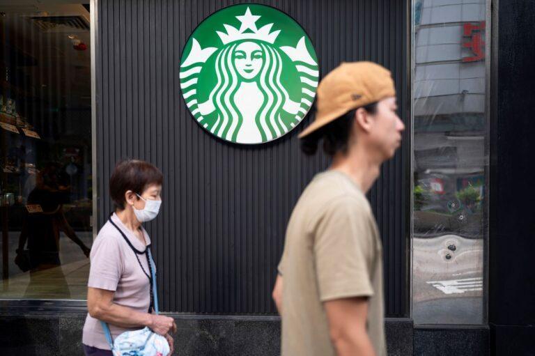 Zdjęcie przedstawia starszą kobietę i młodego mężczyznę przed kawiarnią Starbucks w Hong Kongu