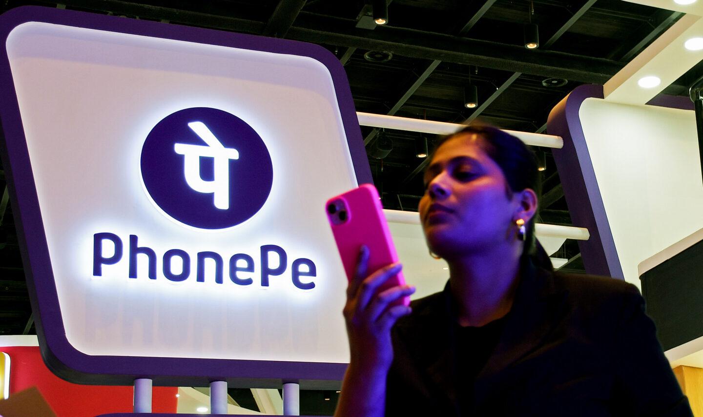 Kobieta ze smartfonem na tle logo aplikacji PhonePe
