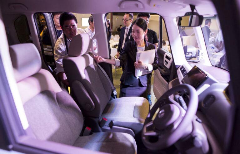 Grupa osób zagląda do wnętrza nowego samochodu osobowego