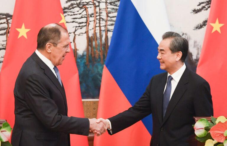 Na zdjęciu Ławrow i Yi podają sobie ręce na tle flag rosyjskiej i chińskiej