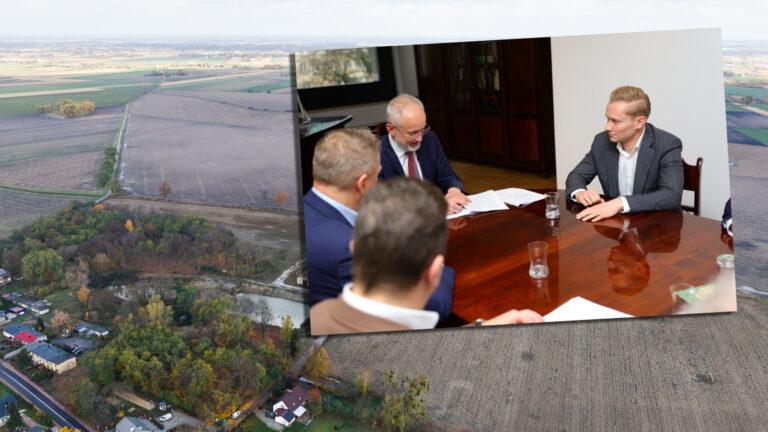 Na zdjęciu prezes Dawtony Piotr Wielgomas podpisuje akt przekazania 160 hektarów ziemi KOWR na tle działki, gdzie ma przebiegać Kolej Dużych Prędkości do CPK