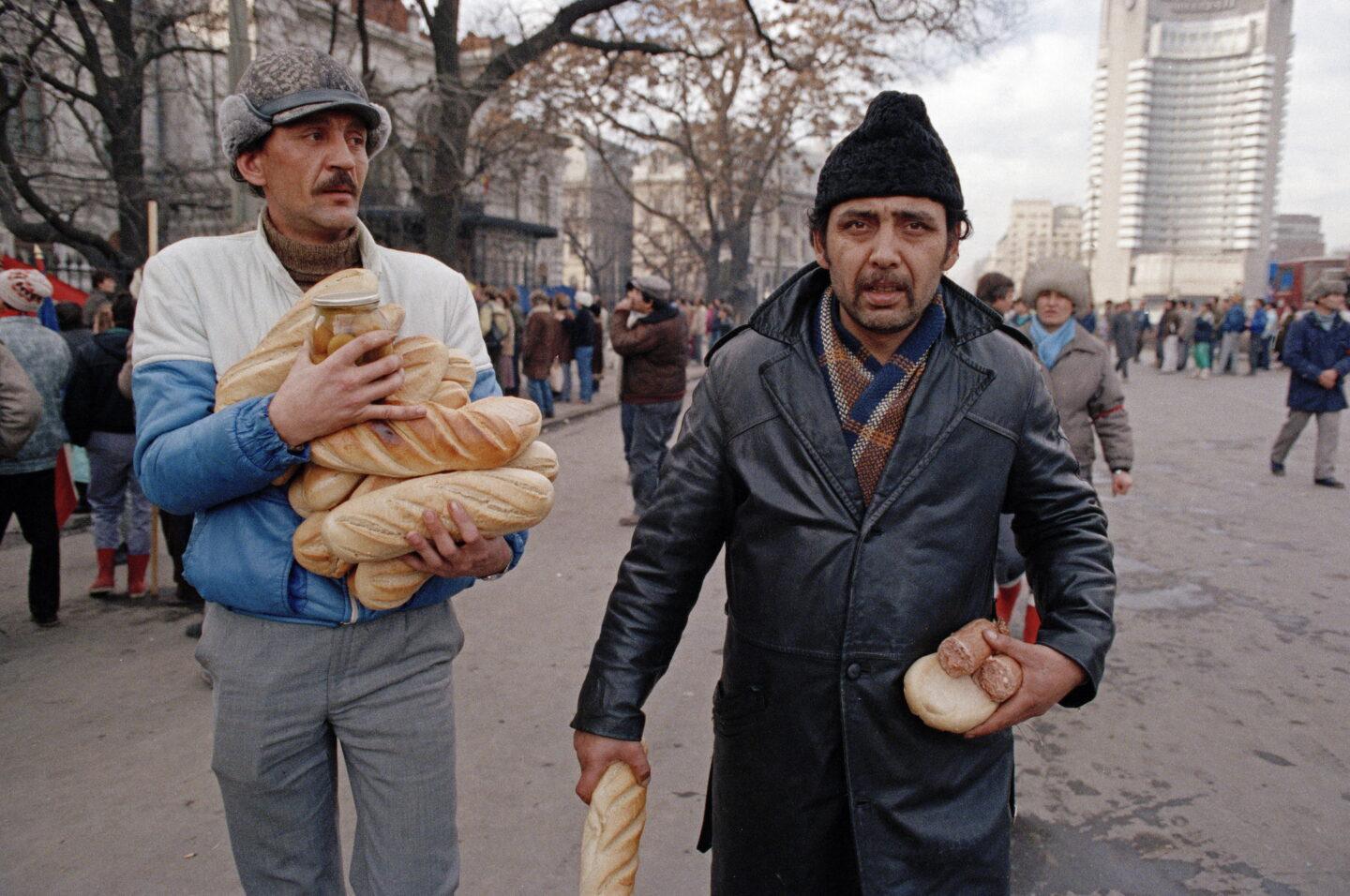 Na zdjęciu z 23 grudnia 1989 r. dwóch mieszkańców Bukaresztu niesie chleb w trakcie walk ulicznych z reżimem Ceausescu