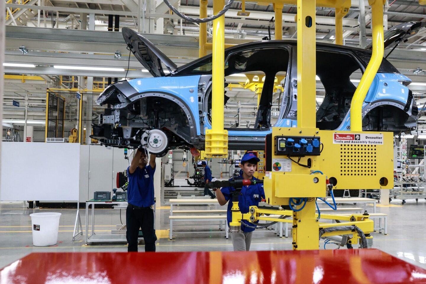 Dwóch pracowników montuje elementy do nadwozia samochodu