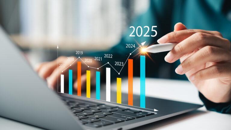 Na zdjęciu ilustracyjnym słupki wzrostów na tle osoby korzystającej z laptopa