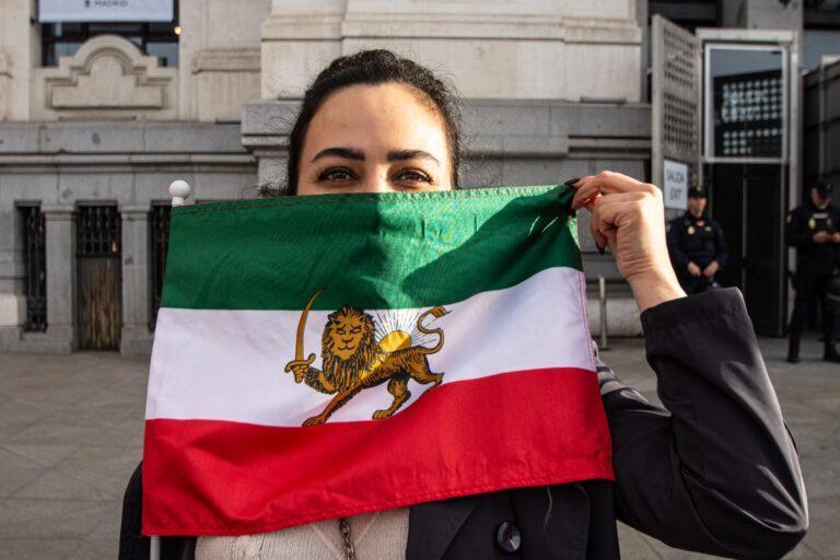 Członkini irańskiej społeczności w Madrycie z flagą Iranu sprzed rewolucji islamskiej, która stała się symbolem obecnych protestów